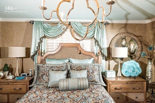 Bedroom with ornate bed, teal accents, and gold chandelier.
