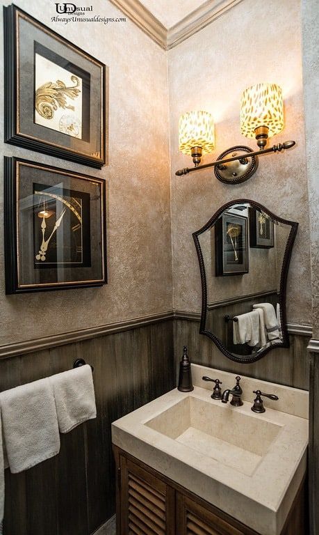 Small bathroom with sink, mirror, art, and patterned wall sconces.