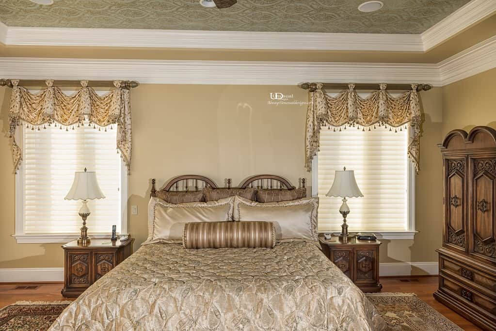 Elegant bedroom with large bed, ornate headboard, nightstands, and detailed window treatments.