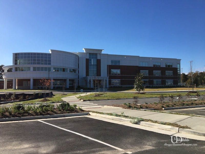 Modern multi-story building with a glass and brick facade, under a clear blue sky.