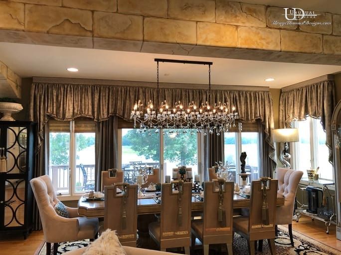 Elegant dining room with chandelier, set table, window view, beige and grey décor.