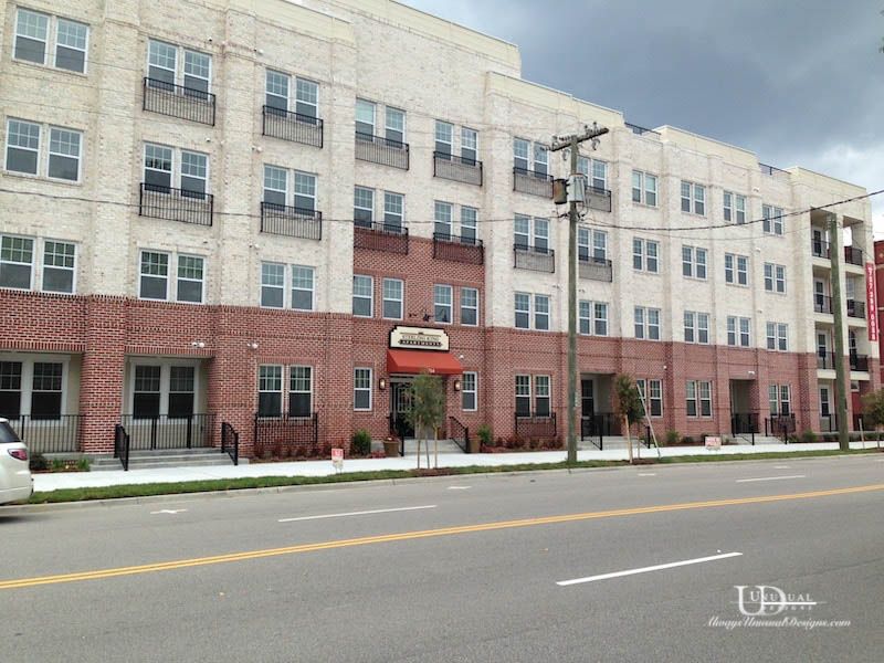 Multi-story brick apartment building on a city street; overcast sky.