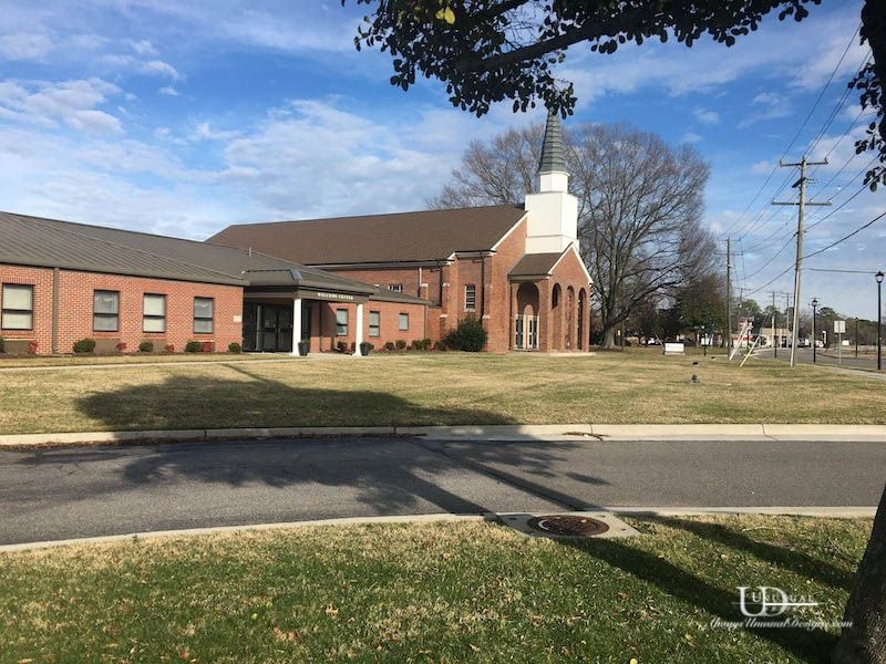 Brick church building with a white steeple on a sunny day.
