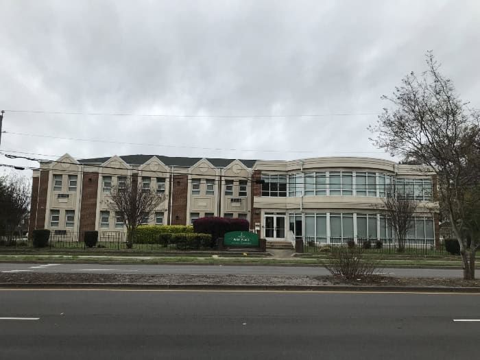 A two-story brick building with white trim under a cloudy sky.