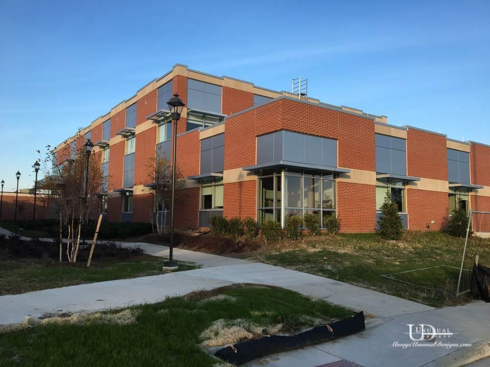 Red brick building with large windows, set against a blue sky, on a sunny day.