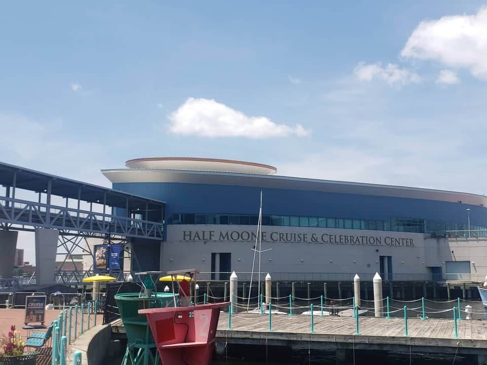 Half Moone Cruise & Celebration Center building at the waterfront with blue sky and pier.