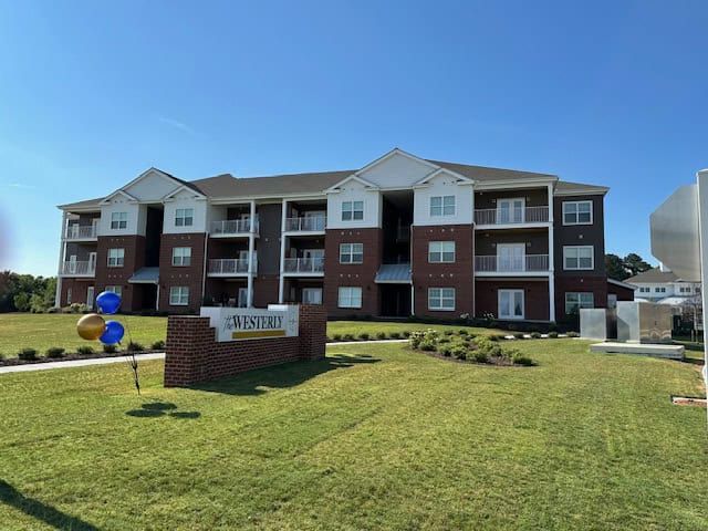 Apartment building with brick exterior, balconies, and a sign that reads 