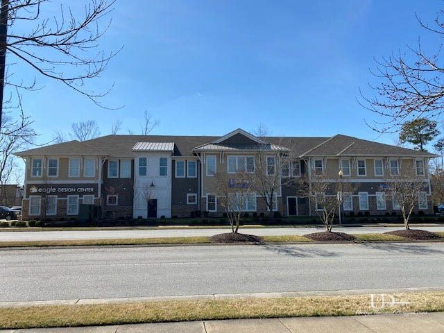 Multi-story commercial building with light and dark brown brick and beige accents under a blue sky.