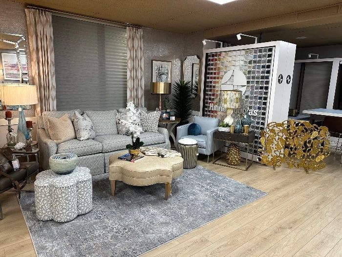 Living room with sofa, armchair, and decorative objects in a showroom setting.