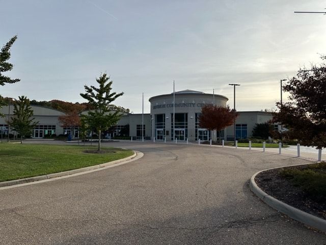 Building with circular entrance, trees, and curved driveway.
