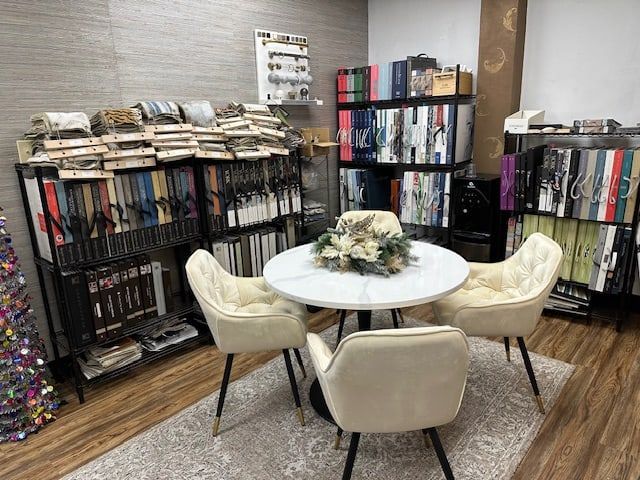 A design consultation space with a round table and three chairs, surrounded by material samples on shelves.