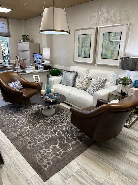 Living room with white sofa, brown leather chairs, rug, coffee table, and framed art.