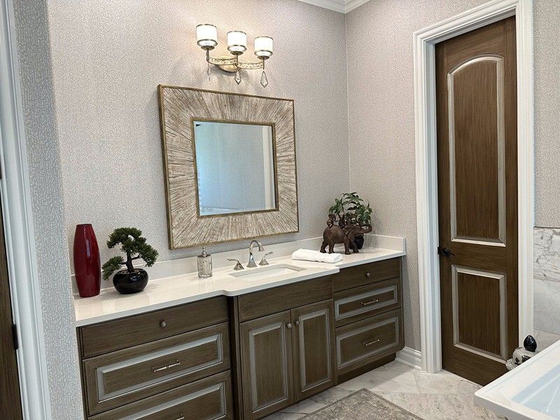 Bathroom with brown vanity, square mirror, and a brown door.
