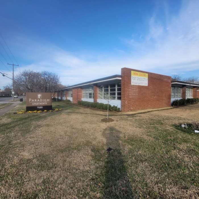 Exterior of Paradigm Institute, a brick building with a sign and a yellow 