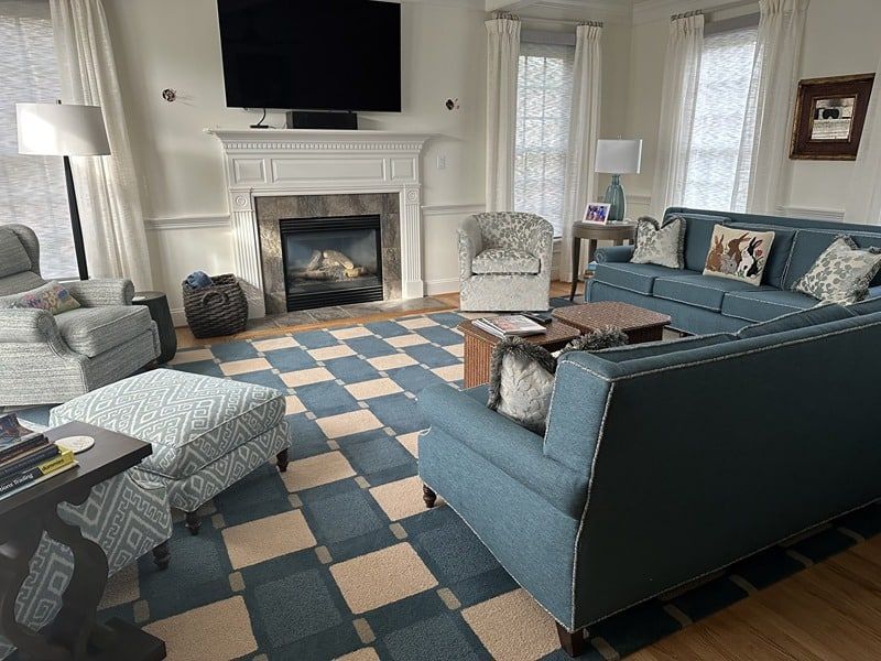 Living room with blue sofas, patterned rug, fireplace, and large TV.