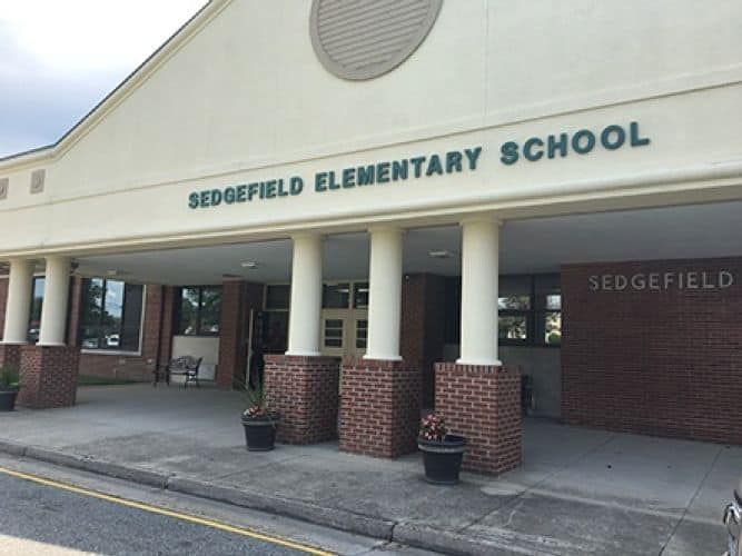 Sedgefield Elementary School entrance with columns and green text on a cloudy day.