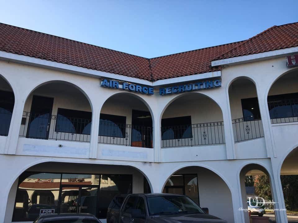 Air Force Bowling building with white arches, red tile roof, and blue signage against a clear sky.