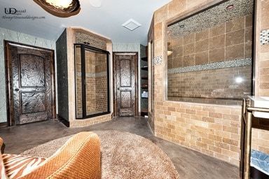 Spacious bathroom with tiled showers, brown doors, and a round rug; brown and beige tones throughout.