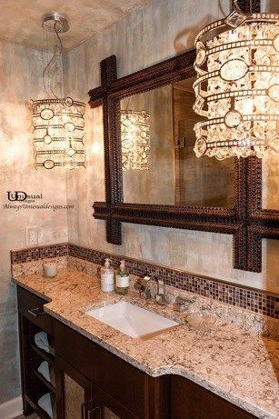 Bathroom with brown vanity, granite countertop, ornate mirror, and decorative hanging lights.