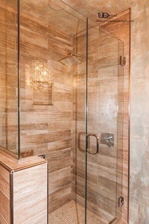 Glass shower enclosure with wood-look tile walls and a rain showerhead.