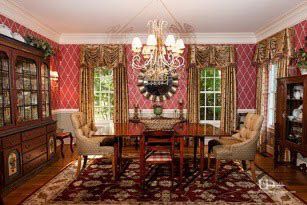 Elegant dining room with red wallpaper, dark wood furniture, chandelier, and patterned rug.