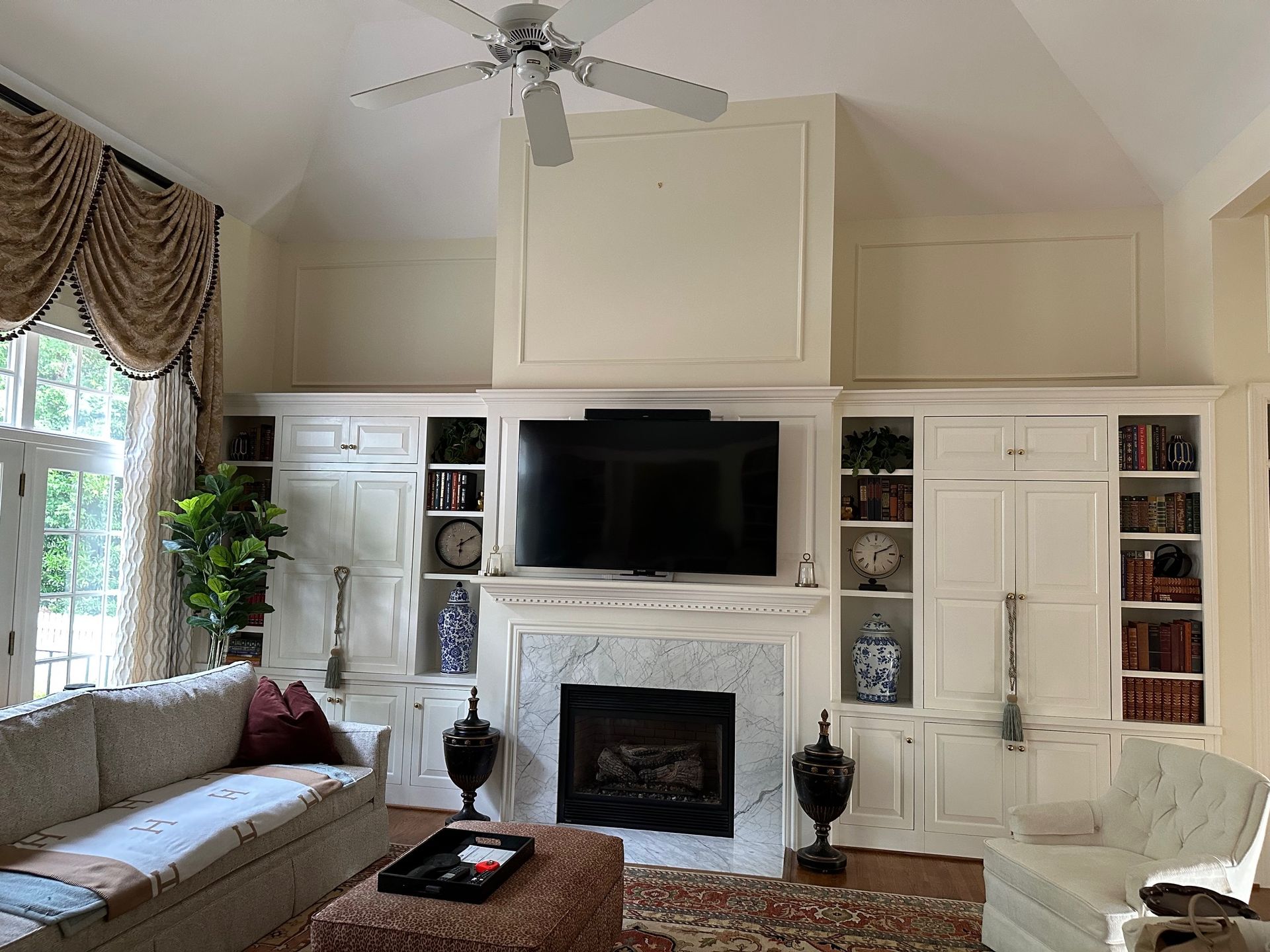 Living room with white built-ins, fireplace, TV, sofa, and curtains.