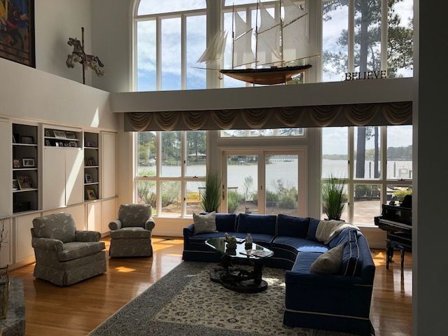 Living room with lake view, blue sectional sofa, hardwood floors, built-in bookshelves, and tall windows.