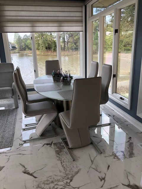Dining room with a round table and six modern chairs, near a window overlooking a lake.