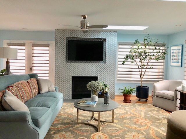 Living room with blue walls, sofa, fireplace with mounted TV, and large rug.