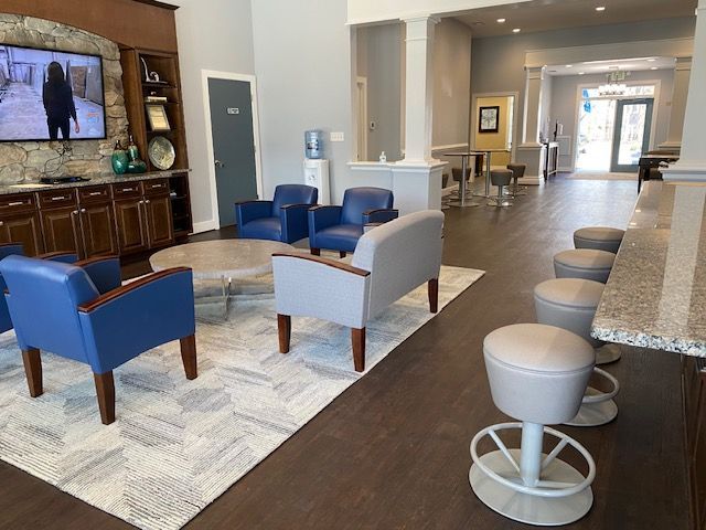 Lounge area with blue and gray seating, a TV, and a bar with stools.