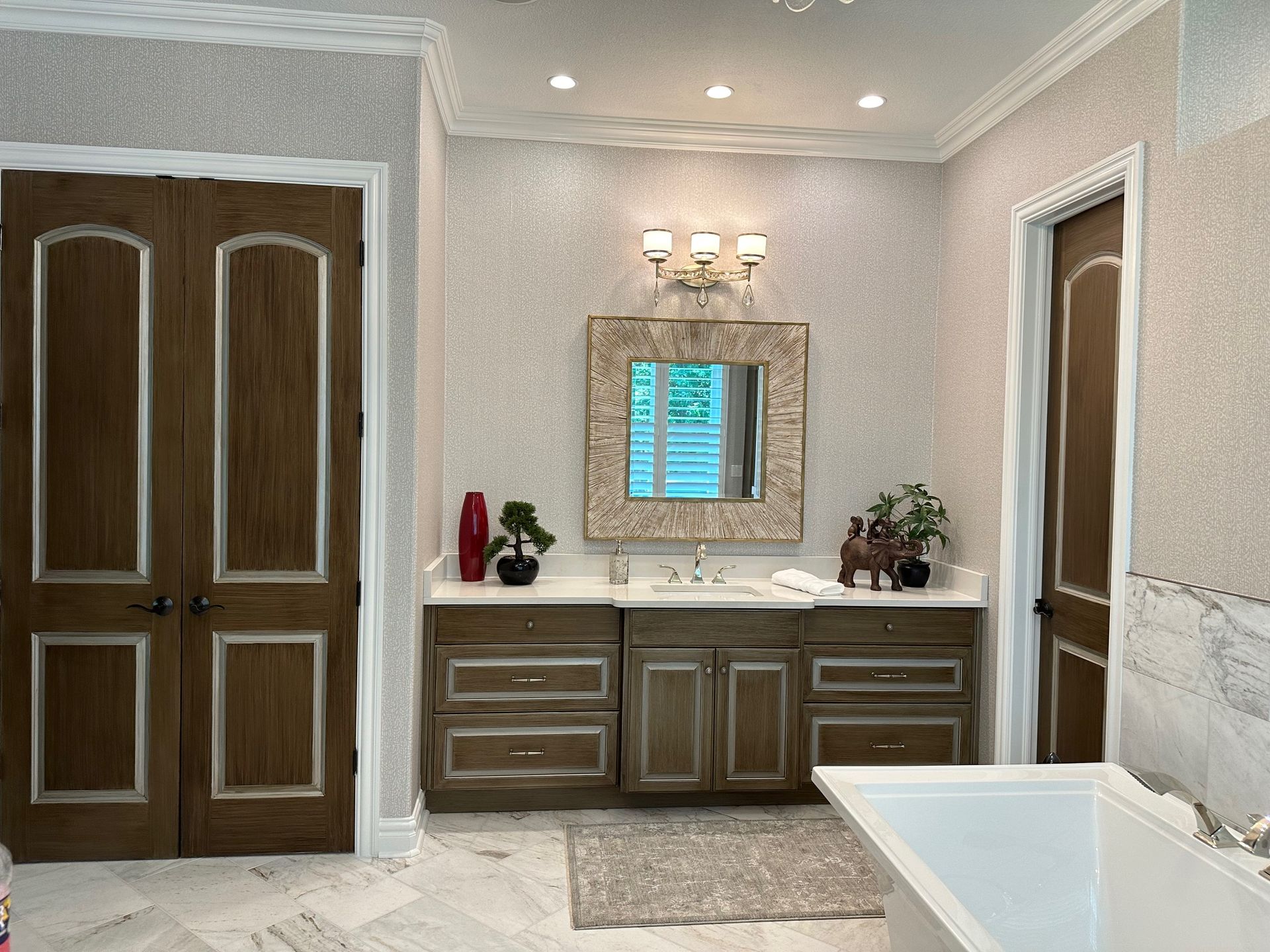 Bathroom with brown cabinets, wood doors, light patterned walls, and a marble floor.