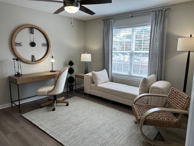 A home office with a desk, chair, chaise lounge, rug, and window with blinds.