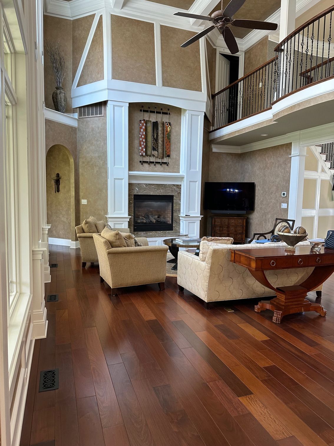 Spacious living room with fireplace, high ceilings, hardwood floors, and a balcony.