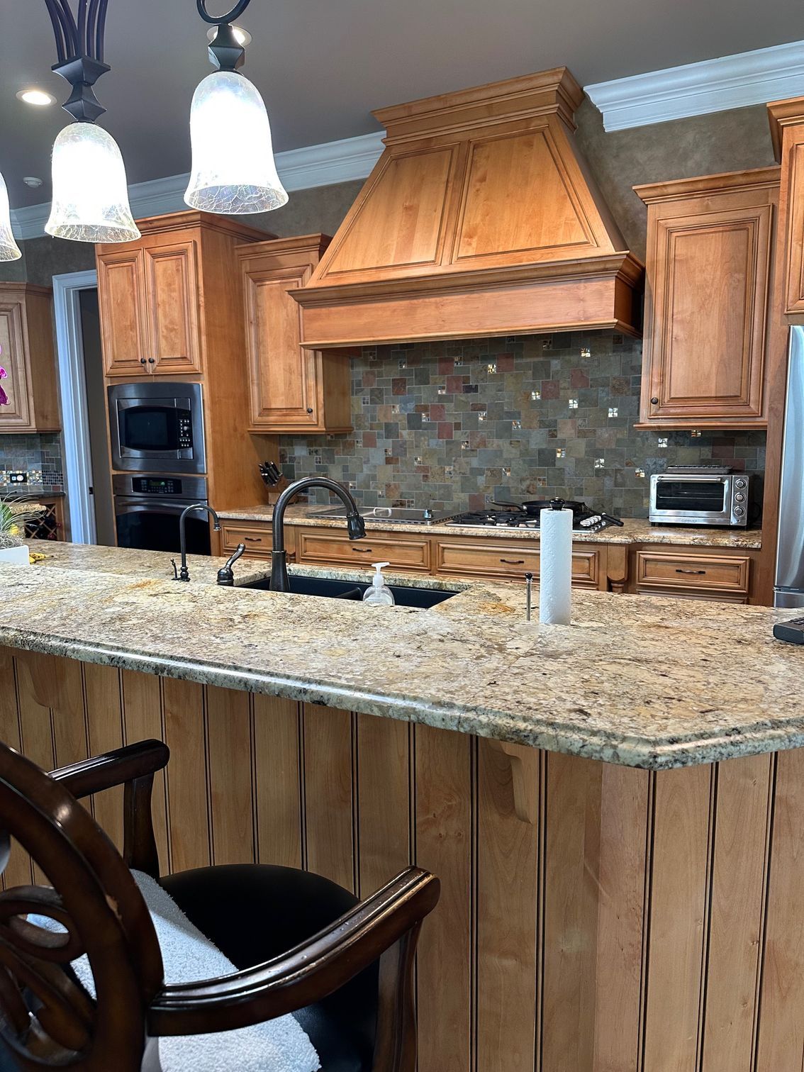 Kitchen with wooden cabinets, granite countertops, and a stone backsplash.