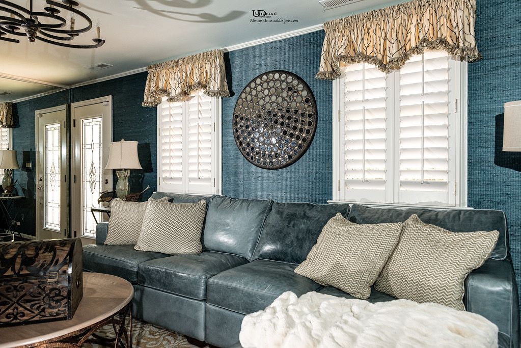Blue leather sofa in a room with blue textured walls, white shutters, and decorative pillows.