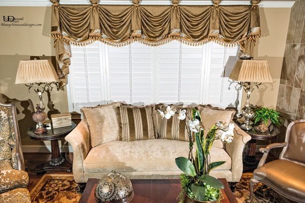 Living room with couch, lamps, and gold window treatment over blinds.