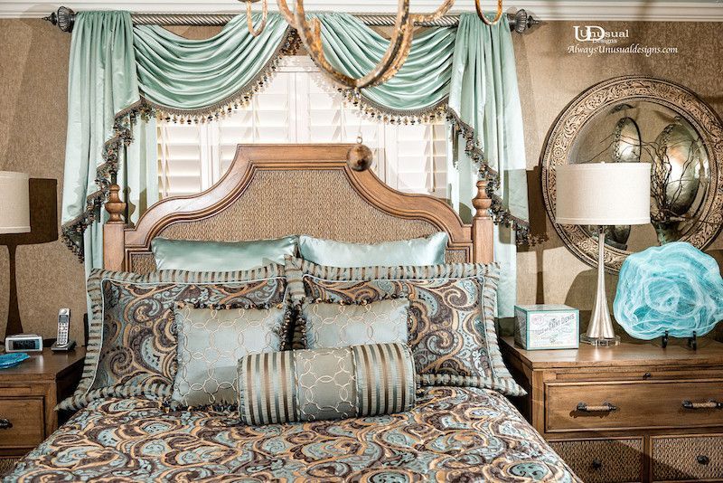 Spacious bedroom with light blue walls, a bed with cream bedding, and a dark armchair.