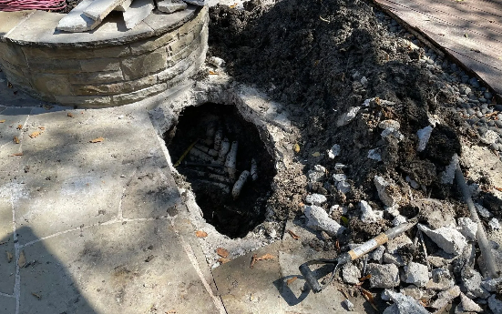 Hole in concrete with ash, possibly a burned-out fire pit.