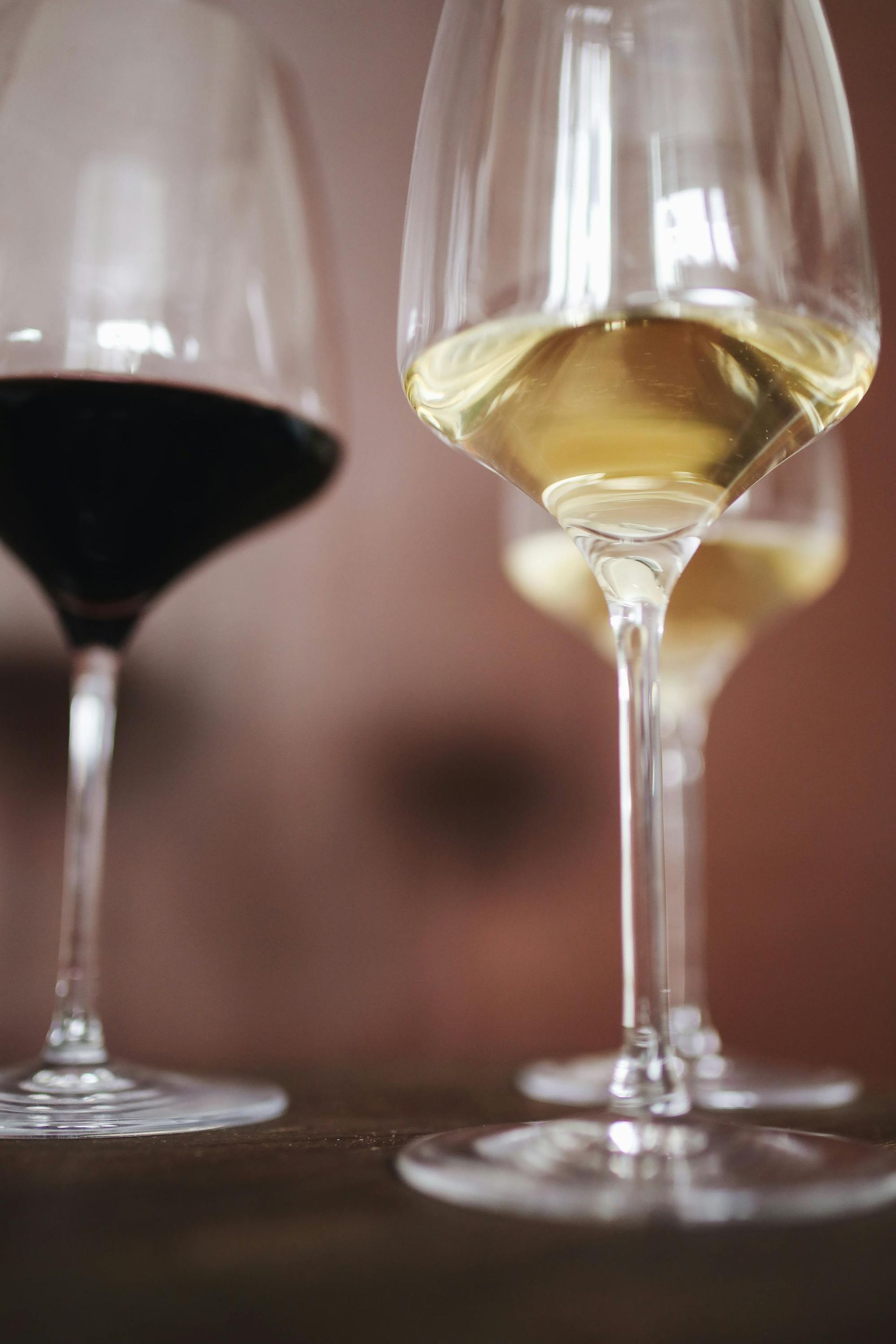 Three wine glasses filled with different types of wine are sitting on a table.