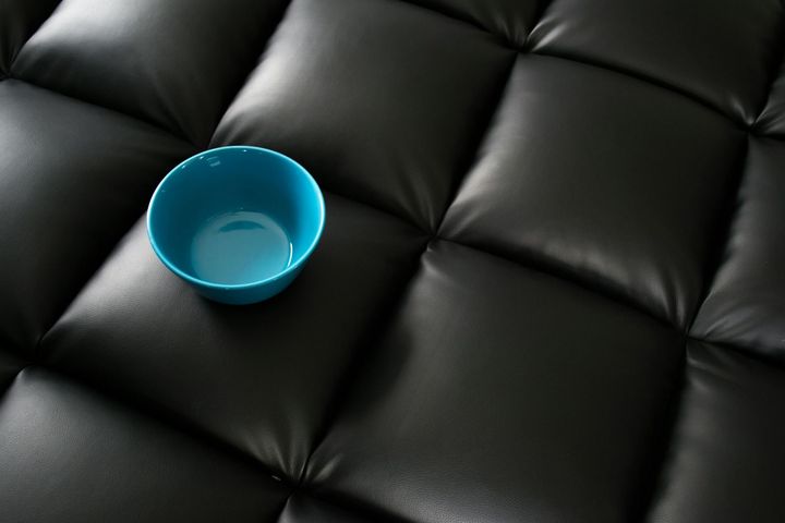Blue bowl on black, tufted leather surface.