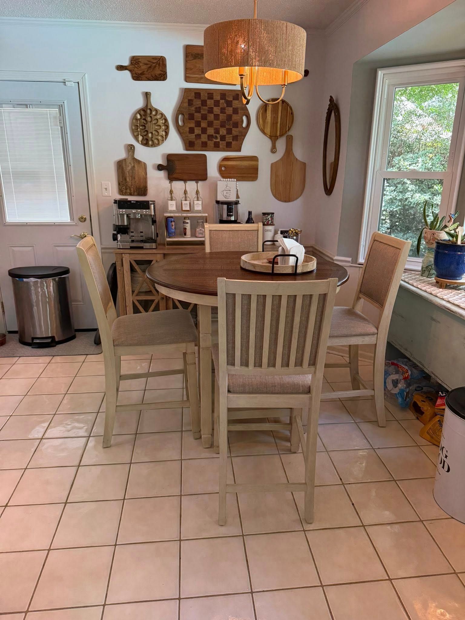 A kitchen dining area with wood table, chairs, and various decorative cutting boards on the wall.