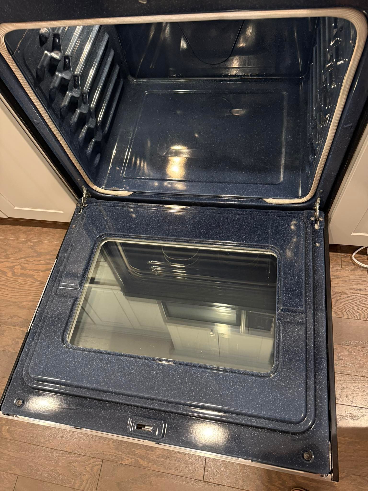 Open oven interior, showing dark speckled walls and glass door.