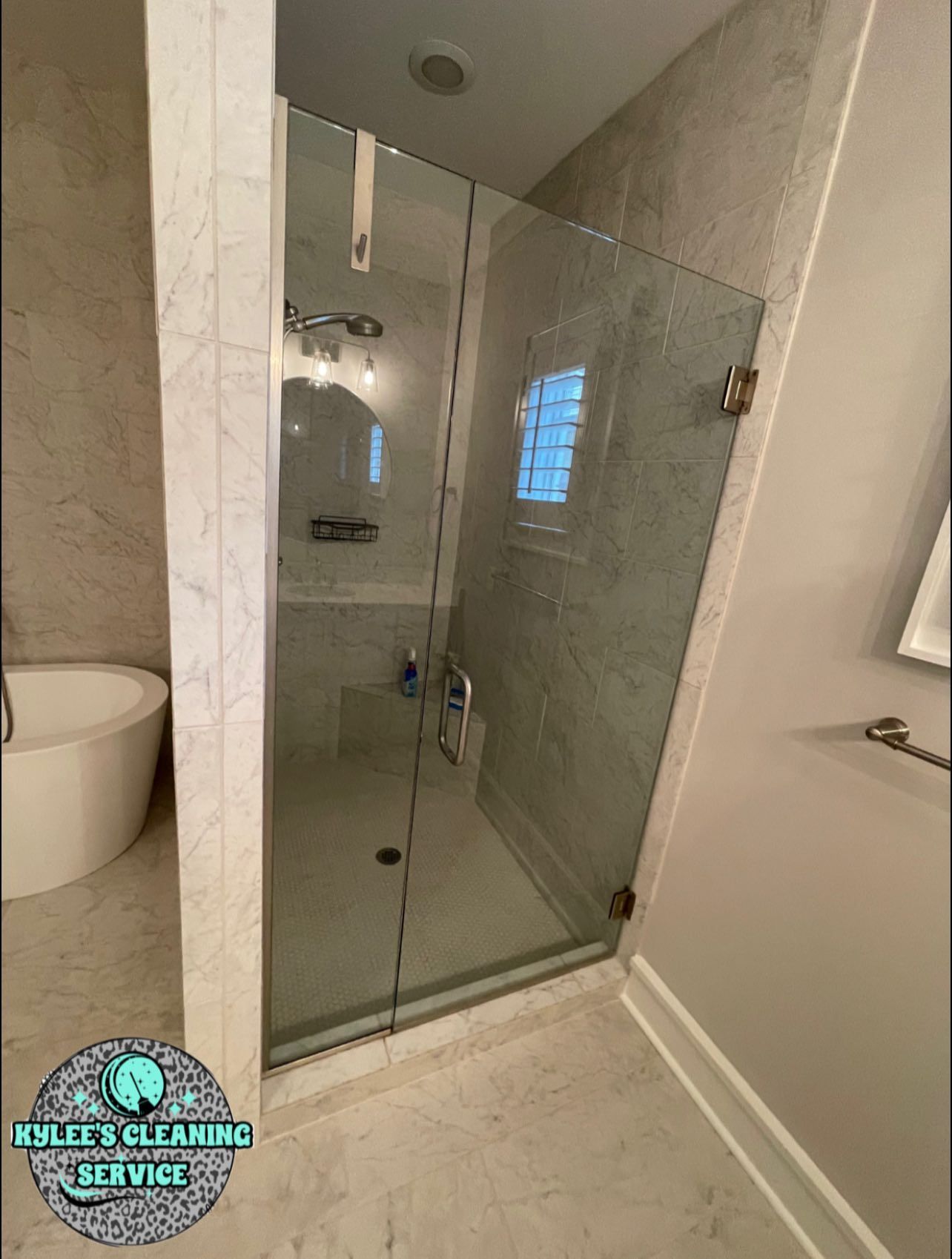 Glass shower with marble tile walls. Bathroom with a bathtub.