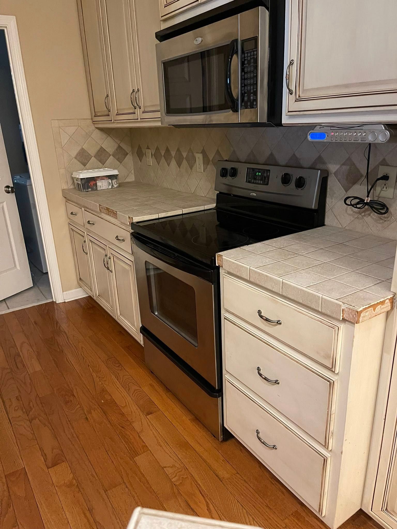 Kitchen with stainless steel appliances, cream cabinets, and tile backsplash. Wooden floor.