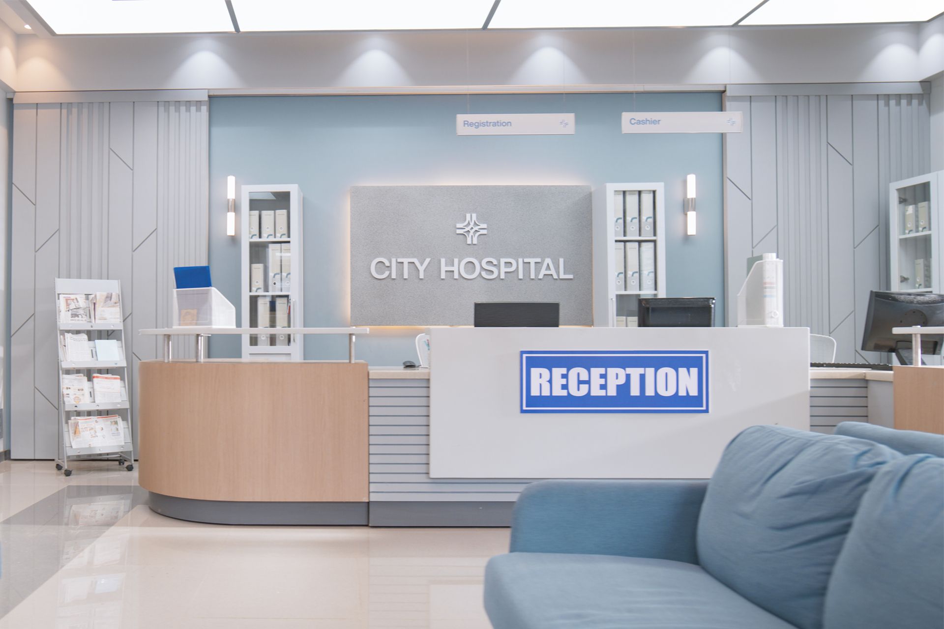Hospital reception area with desk, seating, and signage. Blue, white, and wood tones are prominent.
