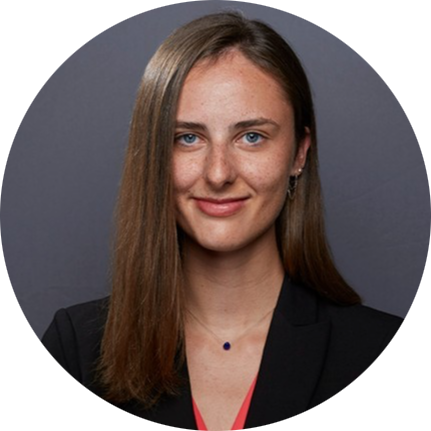 Head-and-shoulders portrait of a woman with straight brown hair, wearing a black blazer on a gray background