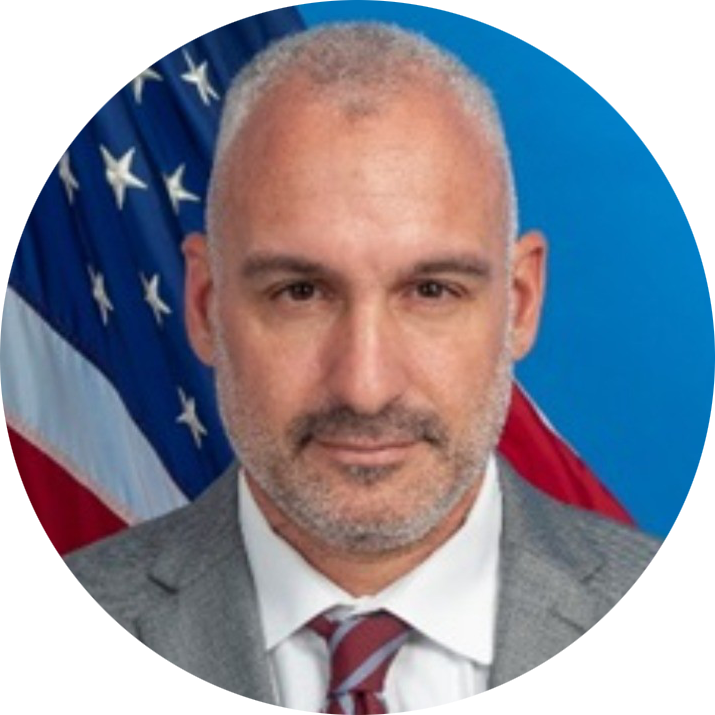 Portrait of a man in a gray suit and striped tie with a U.S. flag backdrop