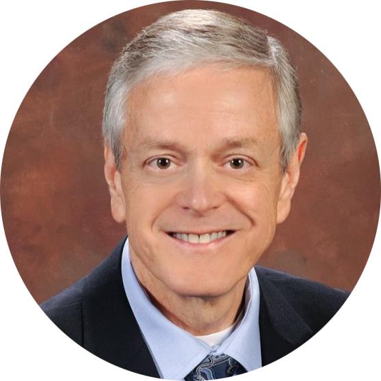 Smiling man in a suit and tie against a brown studio backdrop