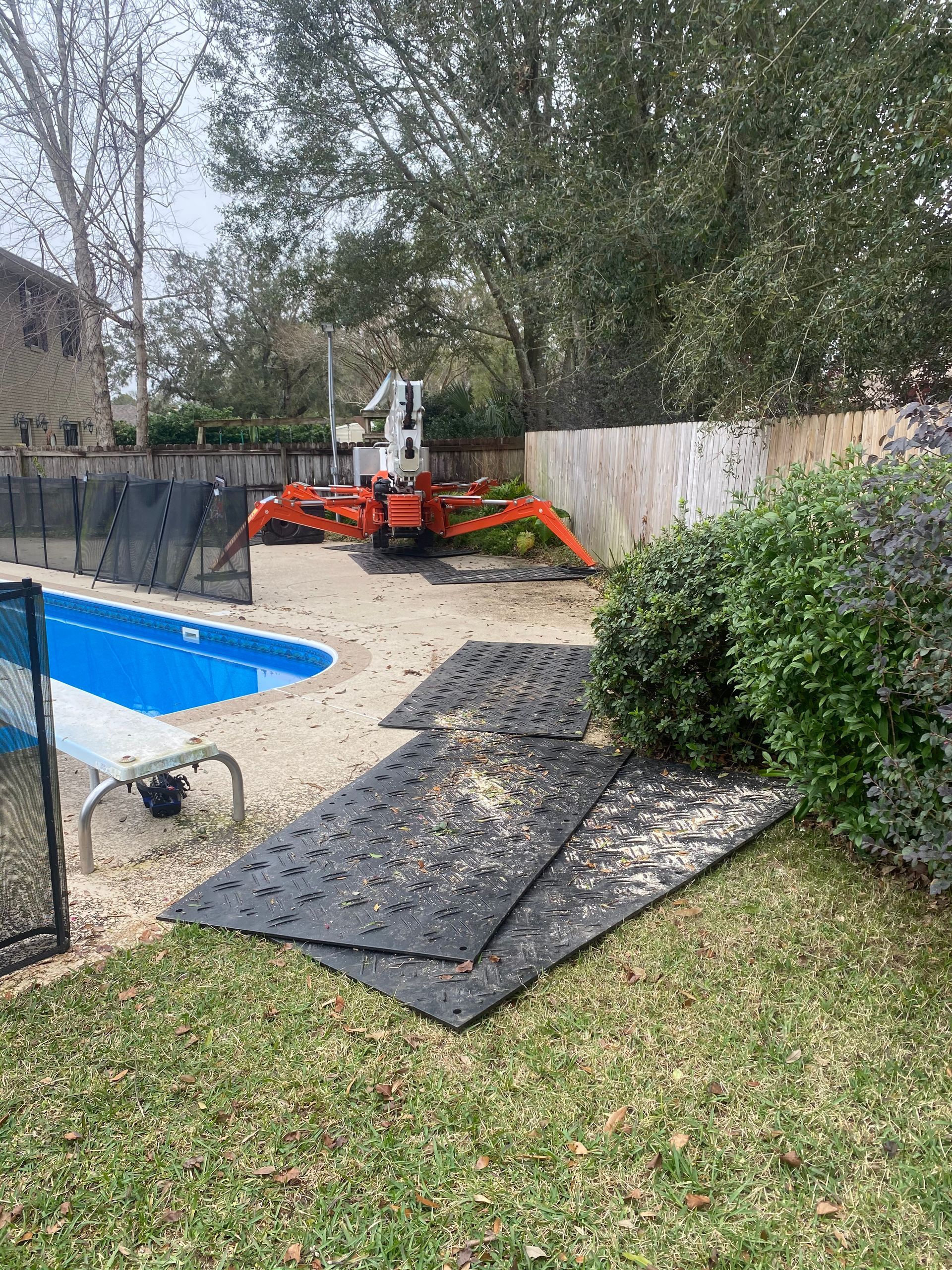 A backyard with a swimming pool and a bulldozer in the background.