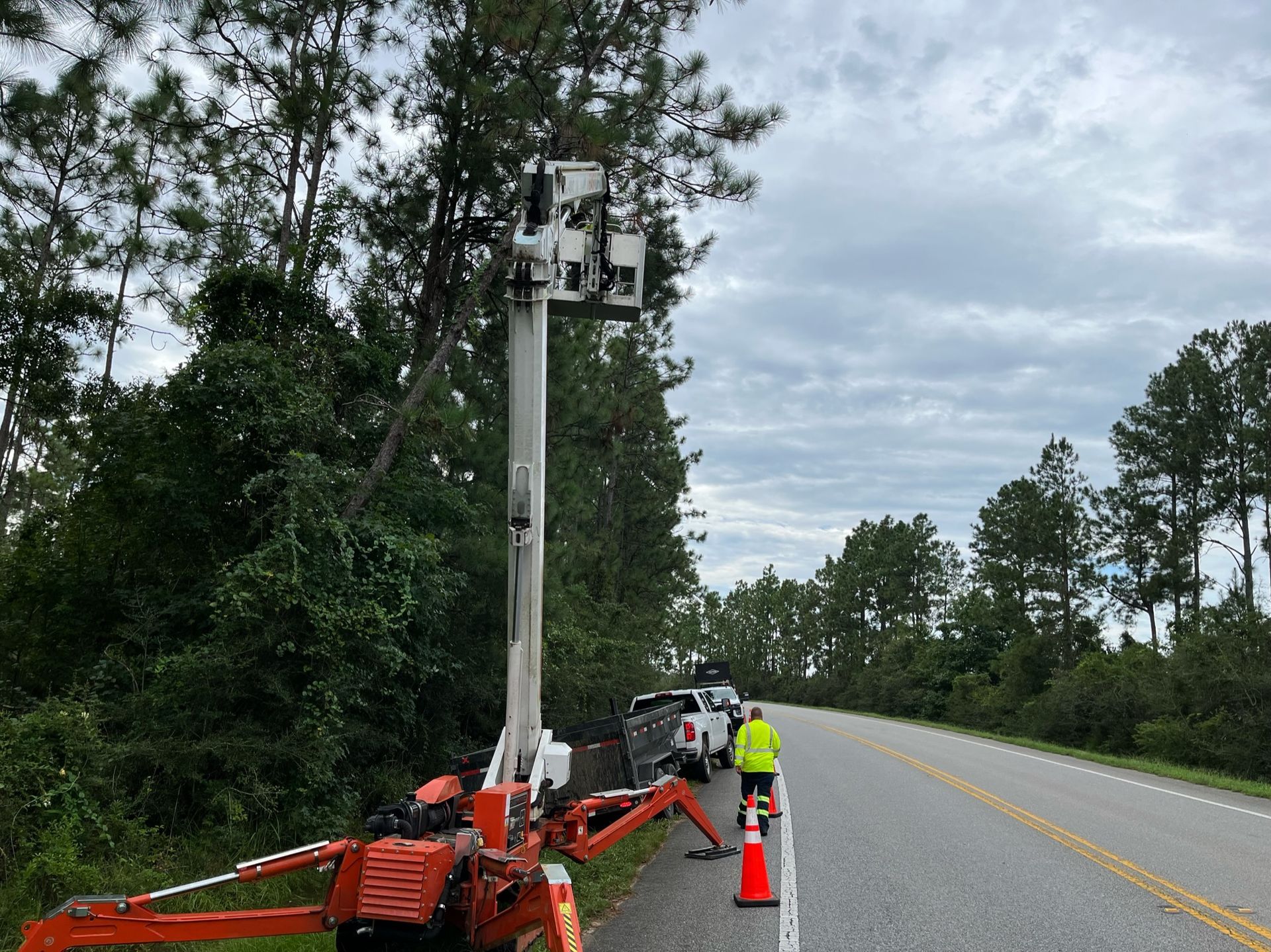 A man is standing on the side of a road next to a crane.